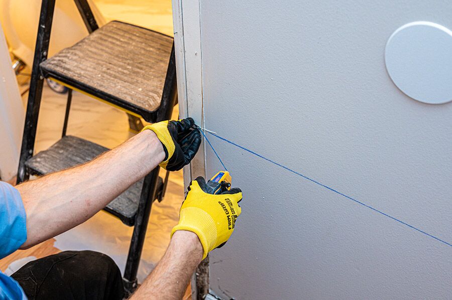 Technician marking a wall for storm damage restoration work