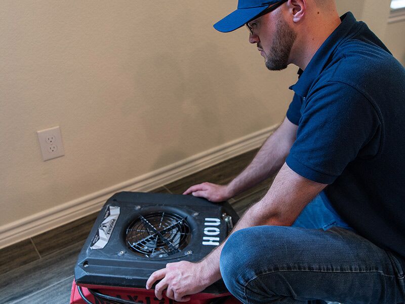 Technician operating drying equipment during storm damage restoration in a home